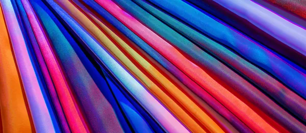 Tecidos coloridos em faixas de lilás, azul e laranja